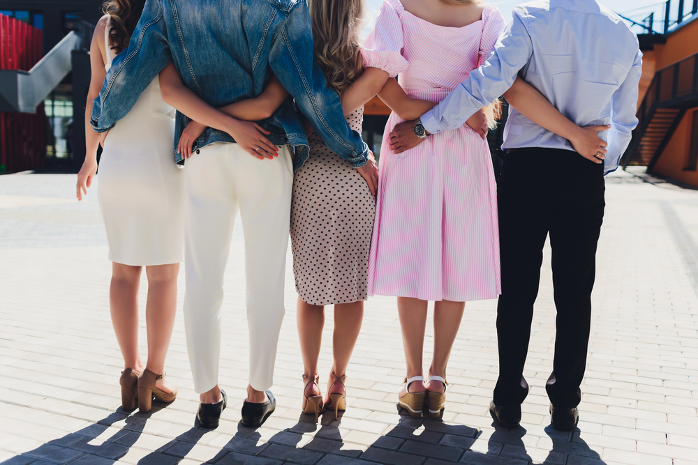 Male and female friends standing next to each other with interlocked arms – suggesting the idea of open relationship dating